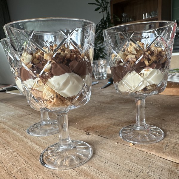 Gelaagde desserts met chocolade, room en noten in kristallen coupes